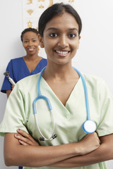 Happy female doctor wearing stethoscope around neck with nurse in the background