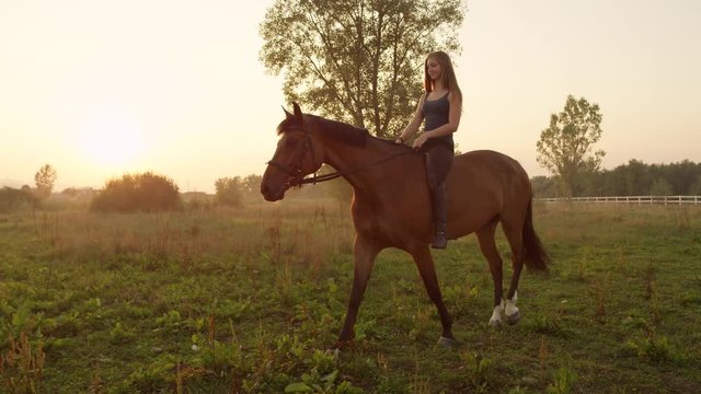 SLOW MOTION: Beautiful smiling girl bareback riding mighty brown horse