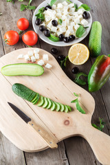 Cooking Greek salad, cutting a cucumber
