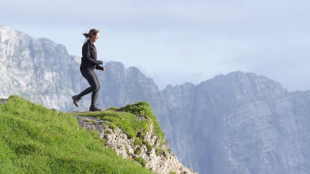 SLOW MOTION: Woman standing on the edge of the mountain with her hands high up