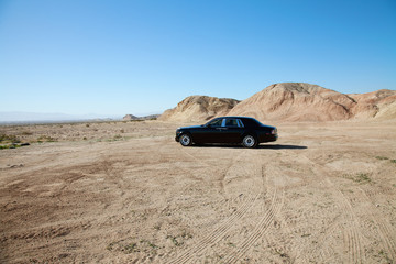 Rolls Royce car parked on unpaved road with tire tracks