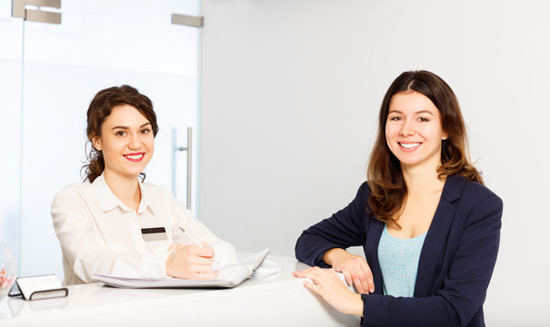 Friendly Woman Behind Reception Desk Administrator With Customer