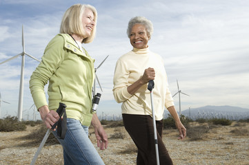 Happy multiethnic senior women hiking near wind farm