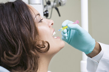 Dentist injecting female patient's teeth in clinic © MDBPIXS