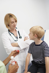 Female doctor looking at boy while nurse holding syrup cup in the clinic