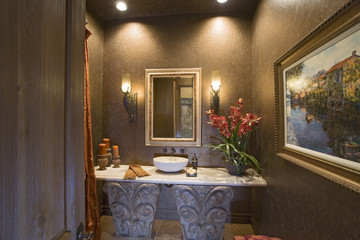Lit sconces and mirror over designed bathroom washbasin