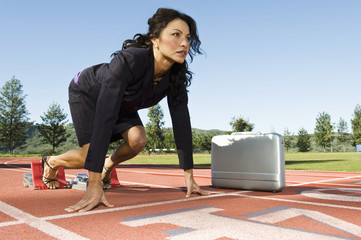 Confident businesswoman with briefcase at starting blocks