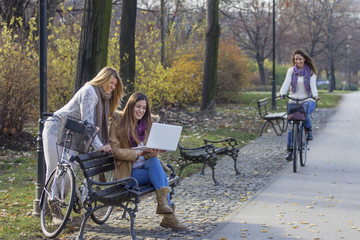 three girls on park with laptop