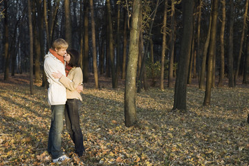 Full length side view of a young couple embracing in forest