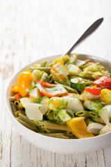 Large white porcelain bowl of pasta and roasted vegetables with a creamy kale sauce on top of white weathered wood
