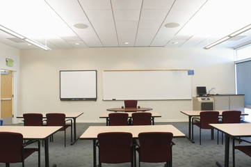 Empty chairs and tables in front of whiteboards in seminar room