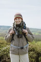 Tuinposter Portrait of smiling young female hiker wearing warm clothing in countryside © moodboard