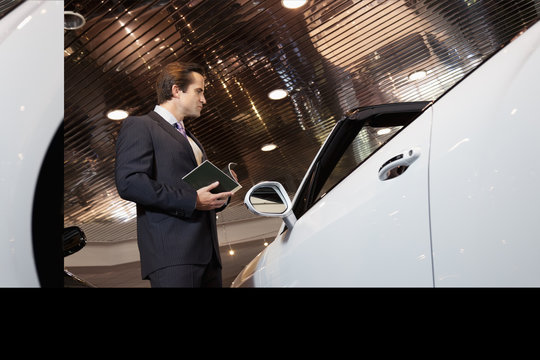 Salesman standing in automobile showroom