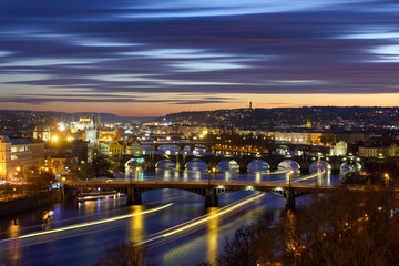 Fototapeta na wymiar River traffic near majestic Charles Bridge during sunset with several boats, Prague, Czech republic
