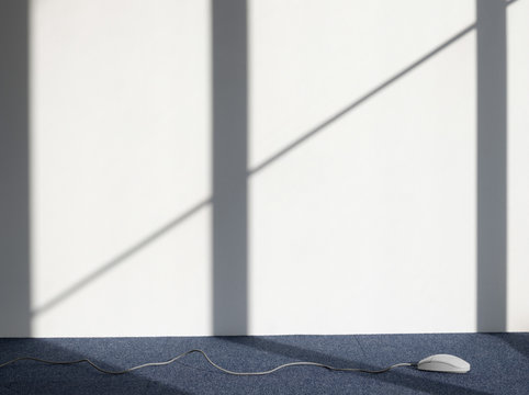 Closeup of a Computer mouse on carpeted floor against white wall