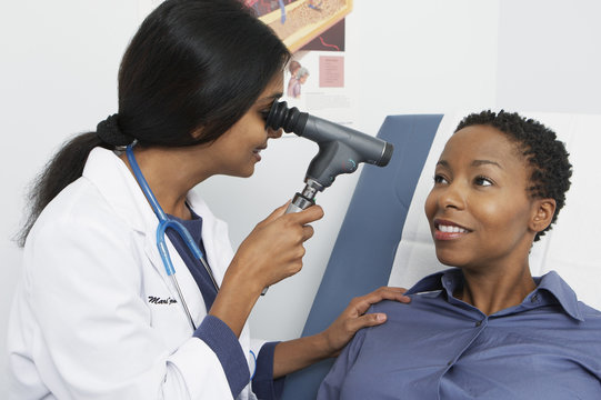 An optometrist checking a female's eye with an eye testing equipment