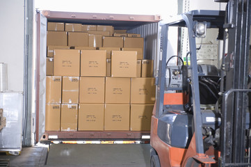 Cardboard boxes and fork lift truck in distribution warehouse