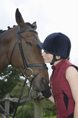 Obraz premium Side view of a young woman kissing a horse outdoors