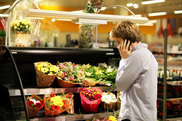 Man buying flowers at a garden center  .Using smarthone