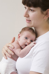 Side view of a mother hugging her newborn baby against colored background