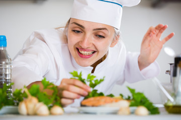 Happy young cook with prepared trout in plate