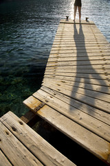 Obraz premium Distance shot of a person standing on wooden jetty by peaceful lake