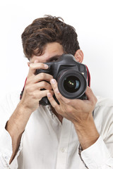Fototapeta premium Young man taking photograph with vintage camera against white background