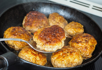 Frying homemade meatballs in black iron pan, in fine broth