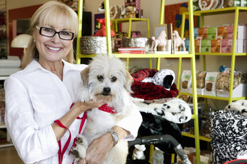 Portrait of a happy senior woman carrying dog in pet shop