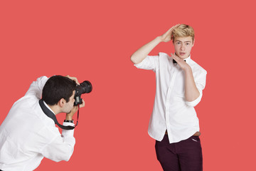 Male actor being photographed by paparazzi over red background