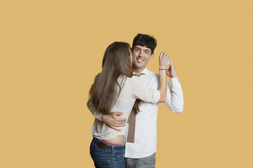 Portrait of young man hugging girlfriend over colored background