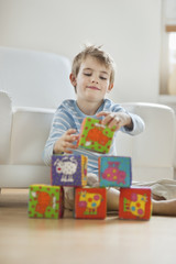 Little boy stacking blocks while sitting on floor