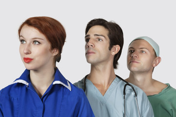 Three medical practitioners looking away against gray background