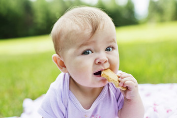 Close-up of infant girl eating biscuit