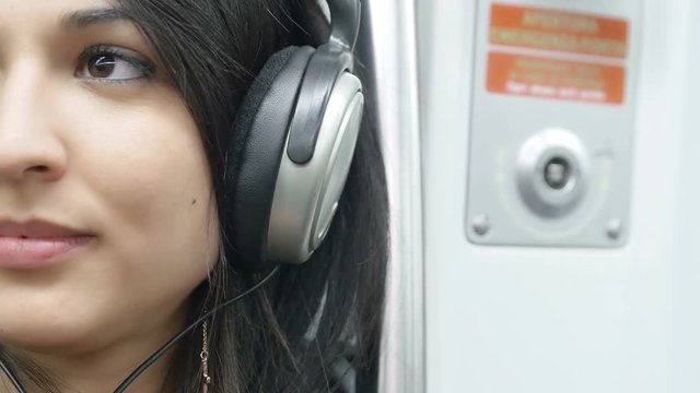 cute young woman listening music in the subway train: relaxing with music