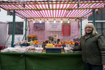 Portrait of a happy senior fruit stall owner standing in market
