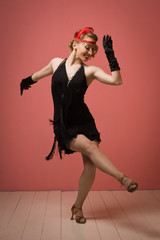 Naklejka premium Ładna aktorka w czarnej sukience retro tańczy Charleston