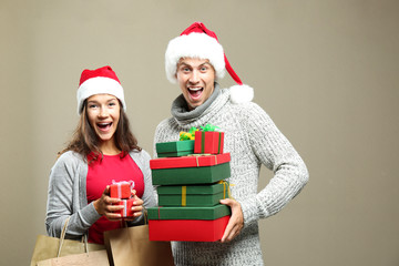 Young couple with Christmas purchases on color background