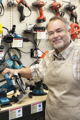 Portrait of a happy salesperson with electric saw in hardware store