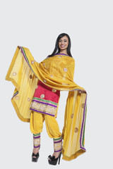 Fototapeta premium Full length of an Indian woman in salwar kameez standing over gray background