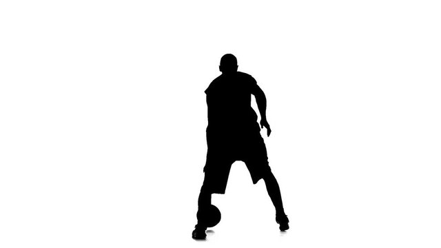 Basketball player spinning passes the ball behind his back. Silhouette