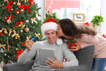 Young couple shopping online with credit card at home for Christmas