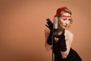 Pretty actress in black retro dress singing with microphone