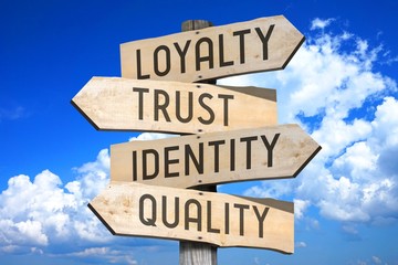 Wooden signpost with four arrows - loyalty, trust, identity, quality - great for topics like brand,...