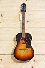 Naklejka premium Acoustic guitar with label isolated on a wood grain wall