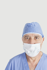 Portrait of senior surgeon with surgical cap and mask over gray background