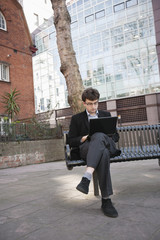 Young businessman working on laptop while sitting on bench