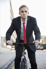 Fototapeta premium Young businessman riding bicycle on street