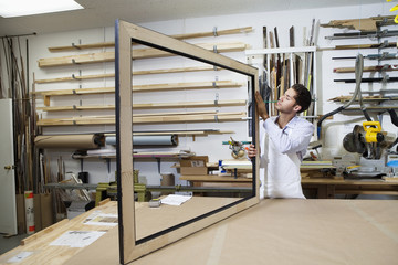 Young craftsman concentrating on making picture frame in workshop