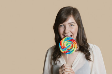 Portrait of a beautiful young woman with lollipop over colored background